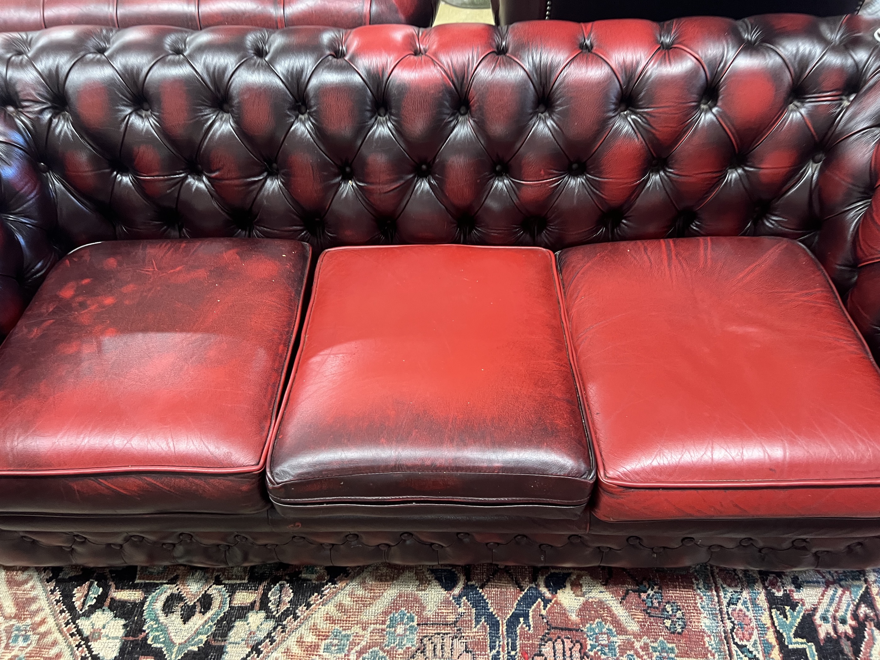 A Thomas Lloyd buttoned burgundy leather Chesterfield sofa, length 200cm, depth 85cm, height 72cm, two leather armchairs and a footstool